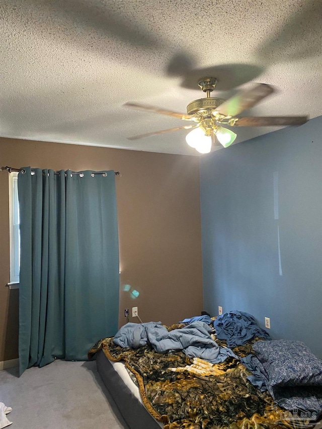 bedroom featuring light carpet, ceiling fan, and a textured ceiling