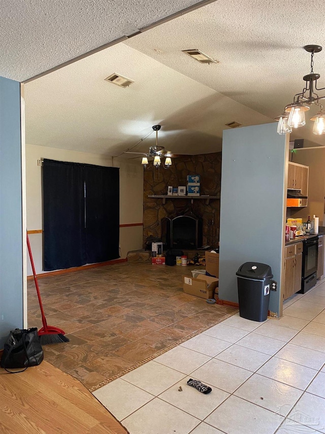 unfurnished living room featuring a ceiling fan, visible vents, a stone fireplace, and a textured ceiling