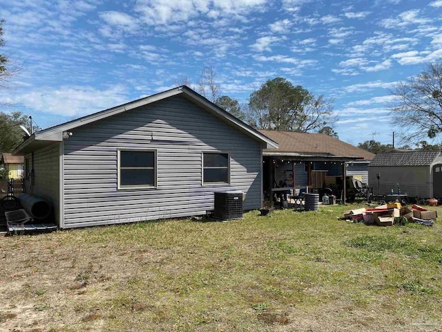 rear view of property featuring a storage unit, central AC unit, a lawn, and an outdoor structure