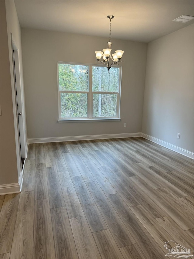 empty room featuring light hardwood / wood-style floors and a notable chandelier