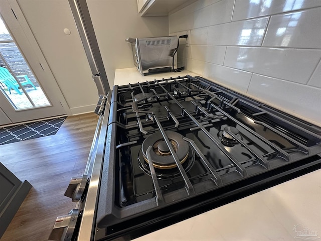 room details featuring dark wood-type flooring, backsplash, gas stove, and cooktop