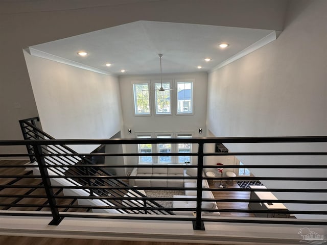 stairs with an inviting chandelier, ornamental molding, and wood-type flooring