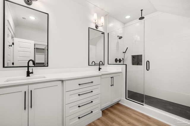 bathroom with wood-type flooring, vanity, walk in shower, ornamental molding, and vaulted ceiling