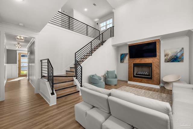 living room with wood-type flooring, crown molding, a notable chandelier, and a fireplace