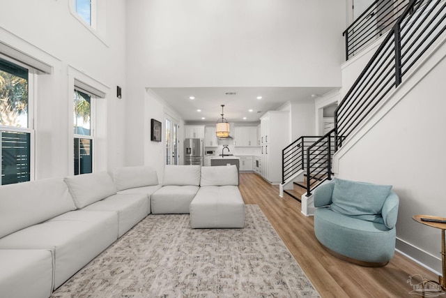 living room featuring light hardwood / wood-style floors, sink, and a towering ceiling