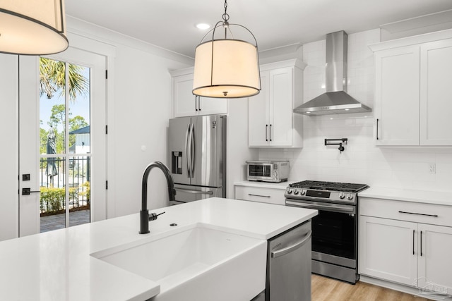 kitchen featuring sink, white cabinets, wall chimney exhaust hood, and stainless steel appliances