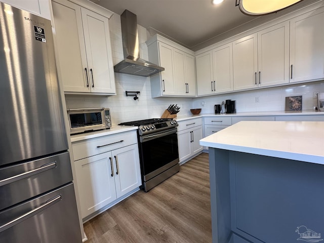 kitchen featuring white cabinetry, backsplash, wall chimney range hood, and stainless steel appliances