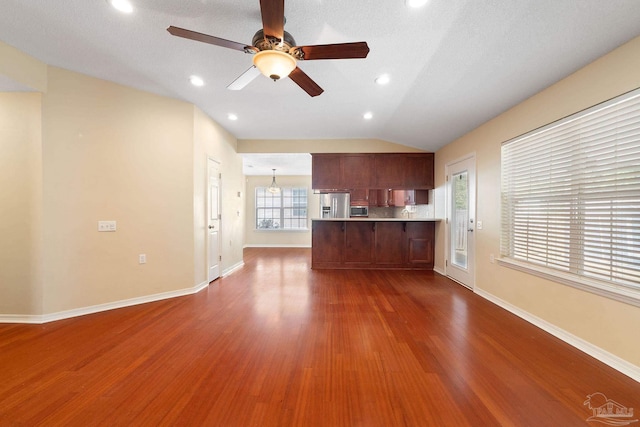 unfurnished living room with hardwood / wood-style flooring, vaulted ceiling, and ceiling fan