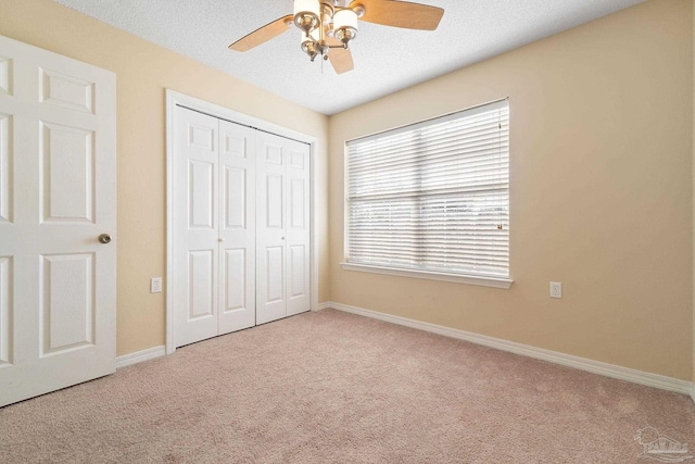 unfurnished bedroom featuring light carpet, a closet, and a textured ceiling