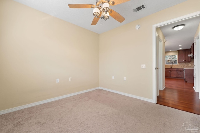 empty room with ceiling fan, sink, and dark colored carpet