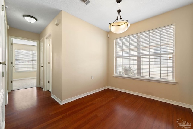 empty room with dark hardwood / wood-style flooring and plenty of natural light