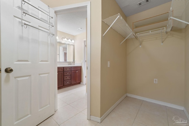 walk in closet featuring light tile patterned floors and sink