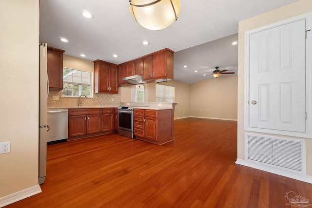 kitchen featuring sink, dark hardwood / wood-style flooring, ceiling fan, stainless steel appliances, and decorative backsplash