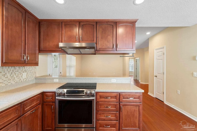 kitchen featuring backsplash, light stone counters, wood-type flooring, a textured ceiling, and stainless steel electric range oven