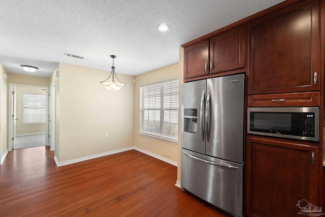 kitchen featuring dark wood-type flooring, stainless steel appliances, decorative light fixtures, and a textured ceiling