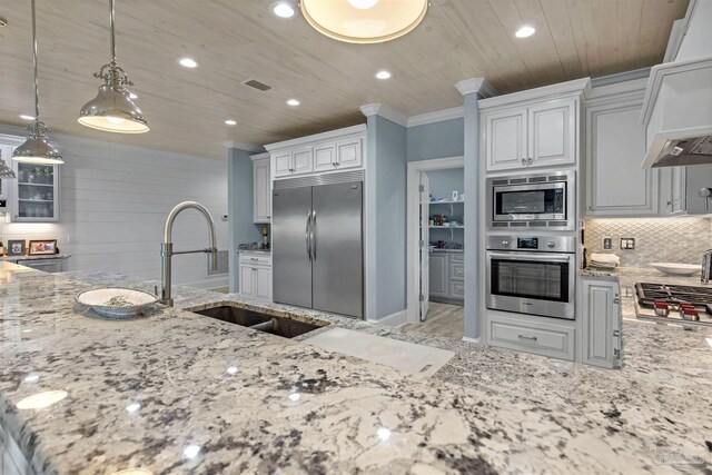 kitchen featuring light stone countertops, decorative backsplash, white cabinets, and built in appliances