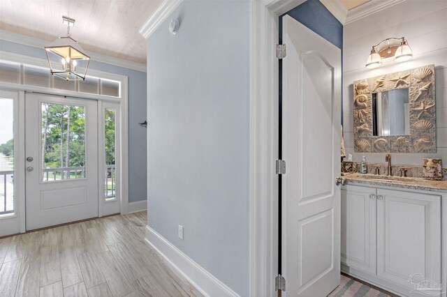 foyer featuring sink, ornamental molding, and light hardwood / wood-style floors