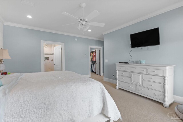 carpeted bedroom with a walk in closet, ensuite bath, ornamental molding, a closet, and ceiling fan