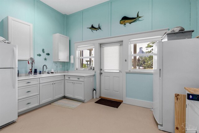 kitchen with white cabinets, sink, and white refrigerator