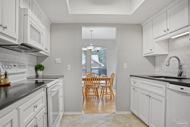 kitchen featuring dark countertops, white appliances, a sink, and light tile patterned floors