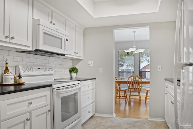 kitchen featuring light tile patterned floors, white appliances, white cabinets, tasteful backsplash, and dark countertops