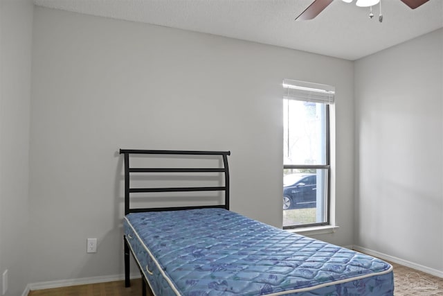 bedroom with a textured ceiling, ceiling fan, and baseboards