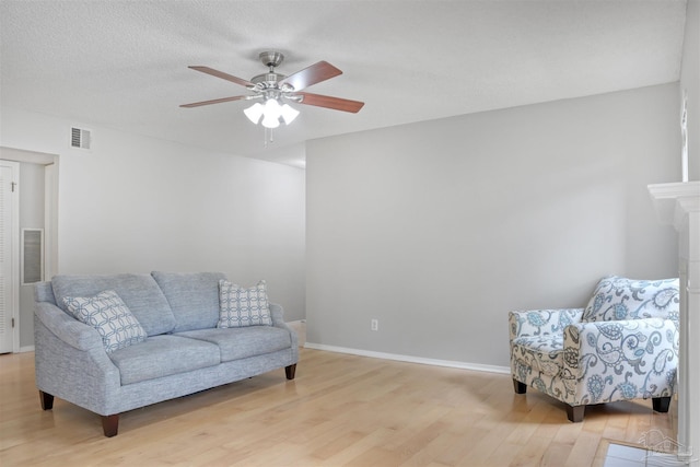 living area with baseboards, visible vents, a ceiling fan, a textured ceiling, and light wood-style floors