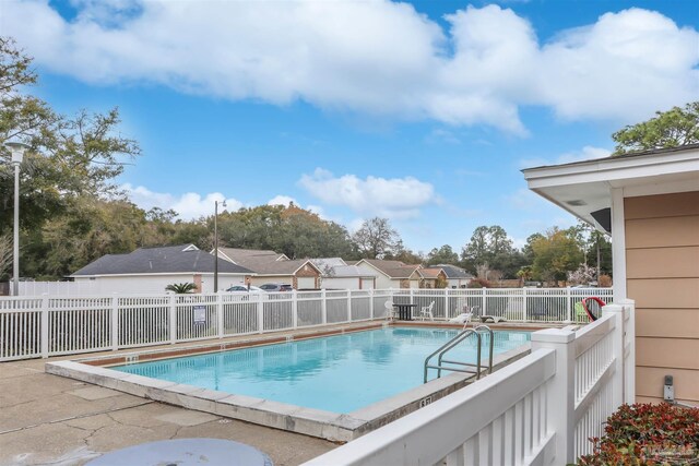 community pool with a residential view and a fenced backyard