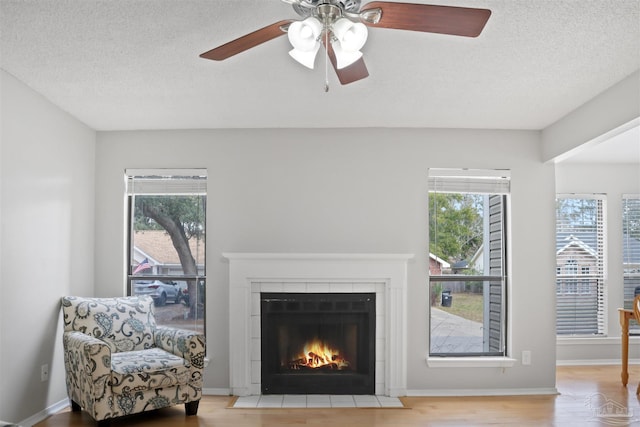 living room with plenty of natural light, a textured ceiling, and a tiled fireplace