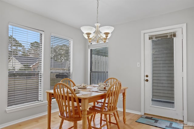 dining room featuring a notable chandelier, light wood finished floors, and baseboards