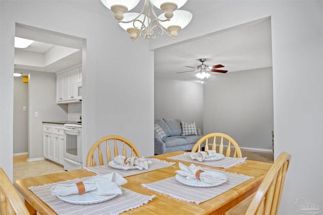 dining space with baseboards and ceiling fan with notable chandelier