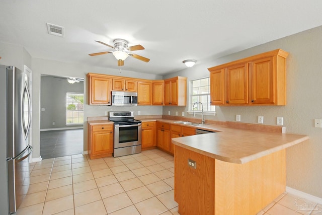 kitchen featuring a healthy amount of sunlight, visible vents, a sink, a peninsula, and stainless steel appliances