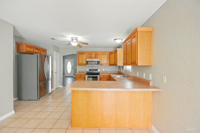 kitchen with a sink, light countertops, stainless steel appliances, and a peninsula