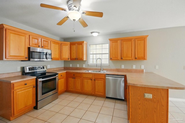 kitchen featuring a peninsula, light countertops, a sink, light tile patterned floors, and stainless steel appliances