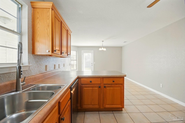 kitchen with stainless steel dishwasher, a peninsula, light tile patterned flooring, brown cabinets, and a sink