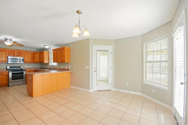 kitchen featuring light countertops, appliances with stainless steel finishes, light tile patterned floors, and a peninsula