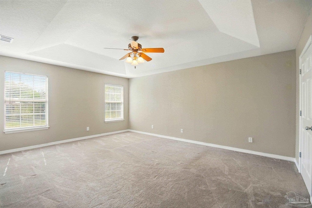 unfurnished room with carpet floors, ceiling fan, baseboards, and a tray ceiling