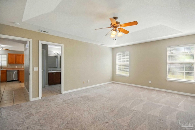 unfurnished room with plenty of natural light, ceiling fan, light colored carpet, and visible vents