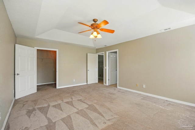 unfurnished bedroom with visible vents, carpet floors, baseboards, ceiling fan, and a tray ceiling