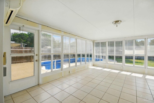 unfurnished sunroom featuring tile patterned flooring and a wall mounted air conditioner