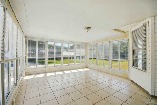 unfurnished sunroom with a water view and tile patterned flooring