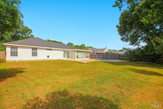 view of yard featuring a fenced in pool, a fenced backyard, and a sunroom