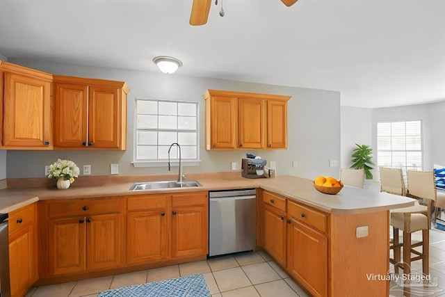 kitchen featuring a kitchen breakfast bar, ceiling fan, stainless steel dishwasher, a sink, and a peninsula