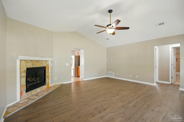 unfurnished living room featuring ceiling fan, visible vents, a fireplace, vaulted ceiling, and wood finished floors