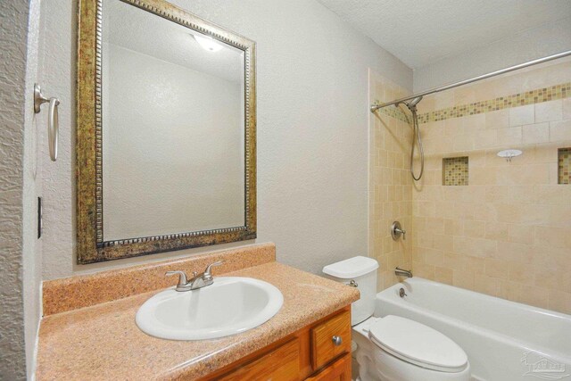 bathroom with a textured wall, vanity, toilet, a textured ceiling, and shower / bath combination