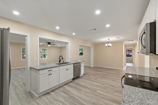 kitchen featuring white cabinetry, sink, appliances with stainless steel finishes, ceiling fan with notable chandelier, and light wood-type flooring