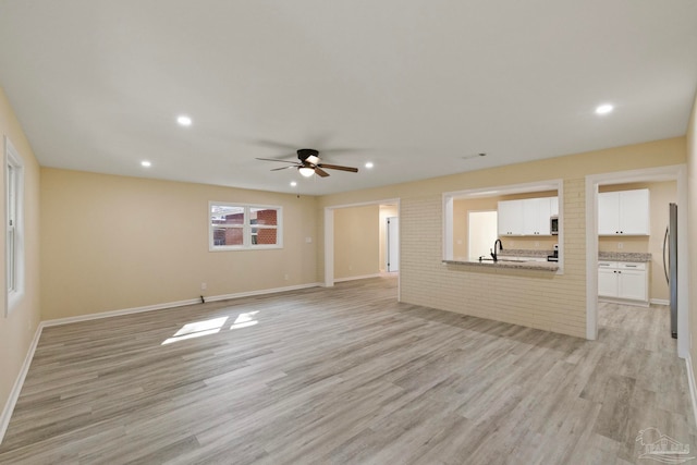 unfurnished living room with ceiling fan, light hardwood / wood-style flooring, and sink