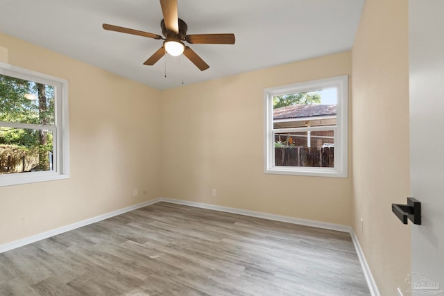 empty room featuring ceiling fan, light wood-type flooring, and a wealth of natural light