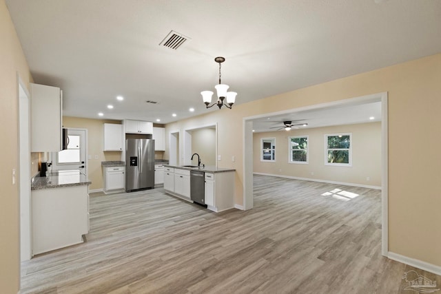 kitchen featuring stainless steel appliances, sink, light hardwood / wood-style flooring, white cabinetry, and hanging light fixtures