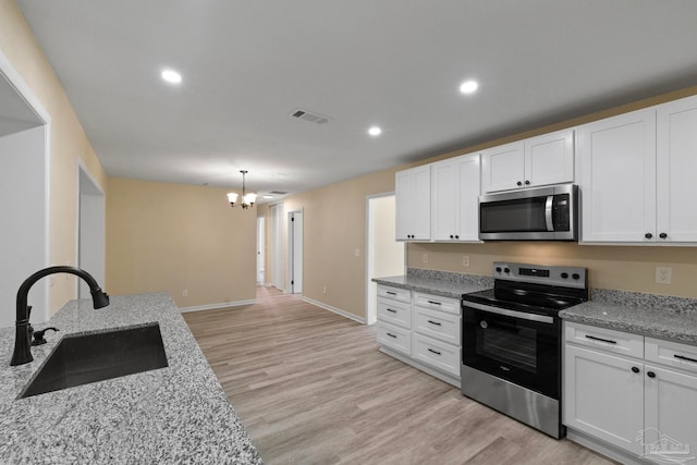 kitchen featuring white cabinetry, sink, an inviting chandelier, appliances with stainless steel finishes, and light wood-type flooring